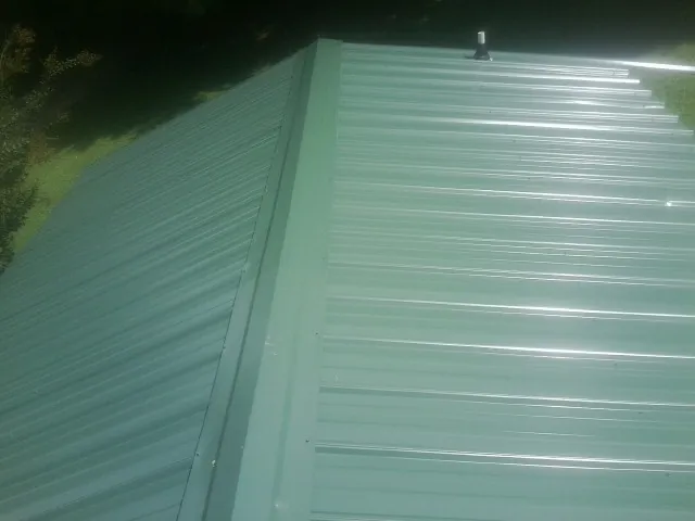 New green metal panels meeting at the ridge of a roof — Flat Roof Repair work by our crew in Nichols